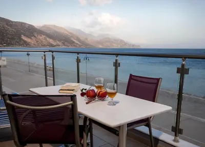 a table with two glasses of wine on a balcony at Paleochora Apartments in Palaiochóra