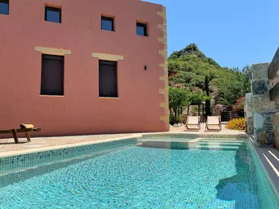 a swimming pool in front of a house with a building at Archon Villa in Pandeleḯmon