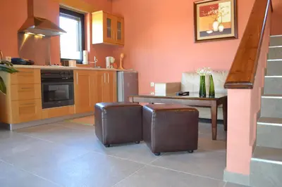 a kitchen with orange walls and a table with stools at Archon Villa in Pandeleḯmon