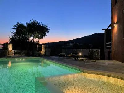 a swimming pool with a sunset in the background at Archon Villa in Pandeleḯmon