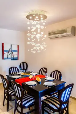 a dining room with a table with chairs and a chandelier at Sandy Point Villas Chania in Agia Marina Nea Kydonias