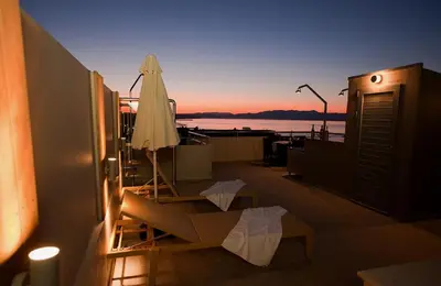 a patio with an umbrella and a table with a bench at Sandy Point Villas Chania in Agia Marina Nea Kydonias