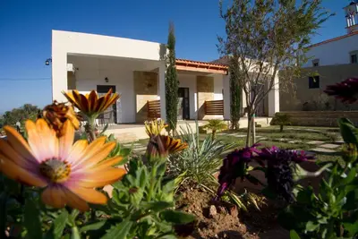 a garden with flowers in front of a house at Agarathos Tradiitonal Apartments & Rooms with Pool Kaliviani -On the road to Balos in Kissamos