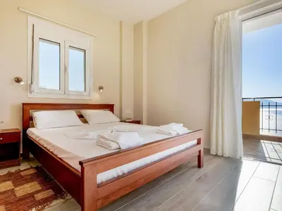 a bedroom with a bed with white sheets and a window at Studio in Ravdoucha with Sea View Balcony in Ravdhoúkha