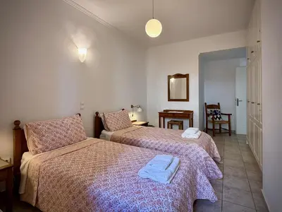 a bedroom with two beds and a table with a chair at Villa Rodi in Gavalochori