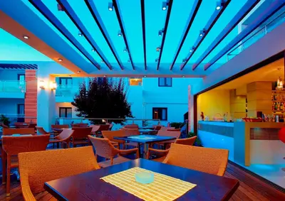 a restaurant with tables and chairs and a blue ceiling at Minos Village in Agia Marina Nea Kydonias
