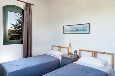 two beds in a room with a window at Traditional Sea Side Cottage in Maleme