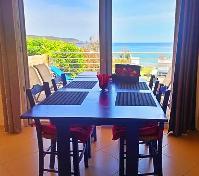 a blue table with chairs and a view of the ocean at Rubini Homes in Agia Marina Nea Kydonias