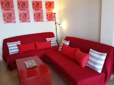 a living room with a red couch and a table at Rubini Homes in Agia Marina Nea Kydonias