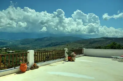 a balcony with potted plants and a view of mountains at Anna-Malai Penthouse in Megála Khoráfia