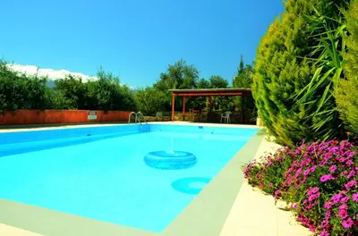 a large swimming pool in a yard with purple flowers at Anna-Malai Penthouse in Megála Khoráfia