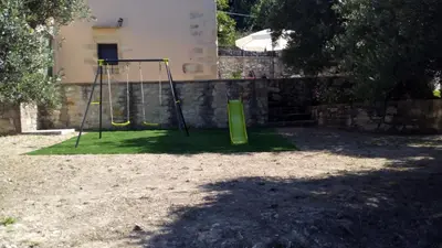 a playground with two swings in a yard at Tzitzifes Stone Mansion in Tzitzifés
