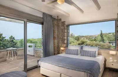a bedroom with a bed and a large window at Cedar Bay Beachside Villas in Palaiochóra