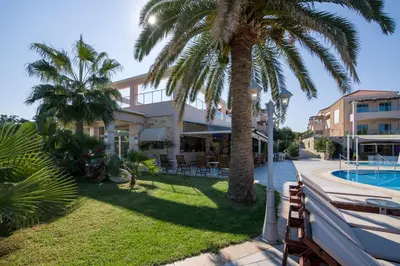 a house with a palm tree and a swimming pool at Isida Hotel Agia Marina in Agia Marina Nea Kydonias