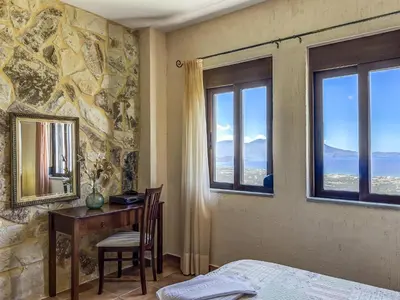 a bedroom with a desk and a bed and windows at Villa Kalliani in Kissamos