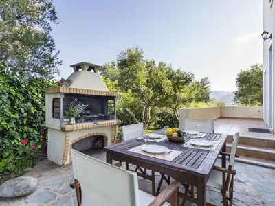 a table and chairs on a patio with a fireplace at Villa Kalliani in Kissamos