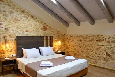 a bedroom with a large bed and a stone wall at Elia Kentron in Chania Town