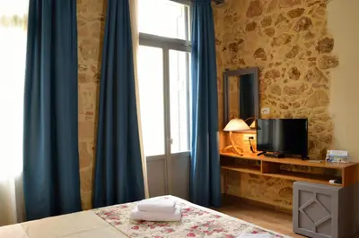 a bedroom with a bed and a window with blue curtains at Elia Kentron in Chania Town