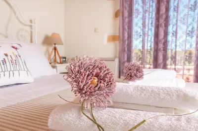 a pink flower sitting on a bed with a towel at Villa Panareti in Kolymvari