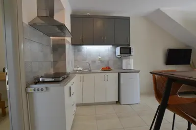 a small kitchen with white cabinets and a sink at Harmony Apartments in Kato Daratso