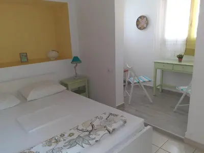 a white bedroom with a bed and a desk at Kampos Rooms in Palaiochóra