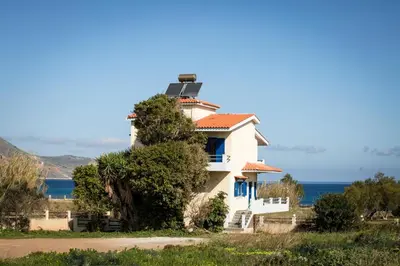 a house on a hill with the ocean in the background at Mantilida Villa & Studio in Kissamos