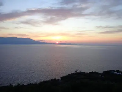 a sunset over the water with the sun in the sky at Michalis Holiday Home in Ravdhoúkha