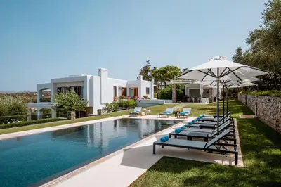 a pool with chairs and an umbrella next to a house at Villa Oleander in Kounoupidhianá