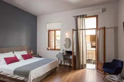 a bedroom with a bed and a desk and a window at Bluebell Luxury Suites in Chania Town