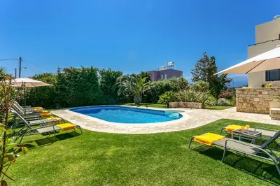 a swimming pool in a yard with chairs and an umbrella at Villa Selena in Stalos