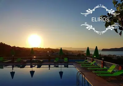 a swimming pool with green chairs and the sunset at Eliros Studios in Stalos