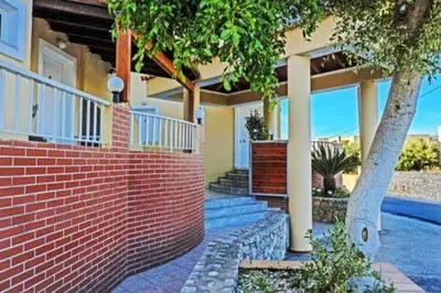 a house with a brick wall and a tree at Eliros Studios in Stalos