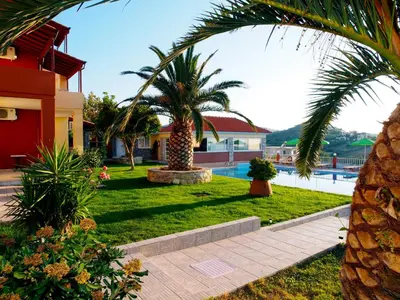 a resort yard with palm trees and a swimming pool at Eliros Studios in Stalos