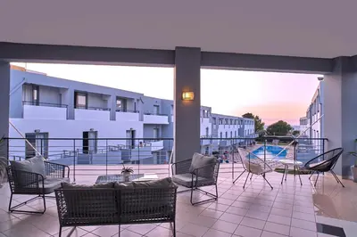 a balcony with chairs and a table and a swimming pool at Sunrise Village Hotel - All Inclusive in Plataniás