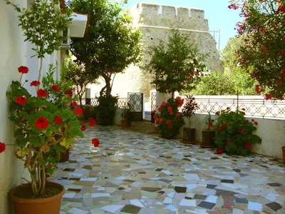 a tiled courtyard with flowers and a castle in the background at Venezian Castle House in Kissamos