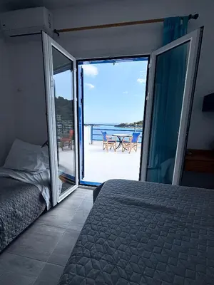 a bedroom with a bed and a view of the ocean at Scirocco Rooms in Loutro