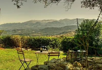 a table and chairs in a field with mountains in the background at Elia House in Megála Khoráfia