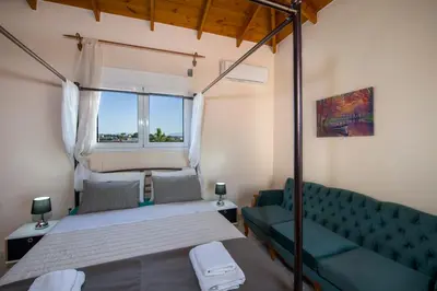 a bedroom with a bed and a couch and a window at Villa Ifigeneia Private Hot Tub Rooms in Kalathas