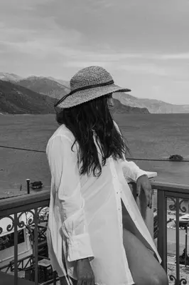a woman wearing a hat sitting on a balcony at Joanna's Place in Palaiochóra
