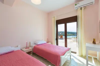 a bedroom with two beds and a window with a view at Kalathas Sunset Villa in Kalathas