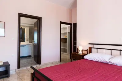 a bedroom with a red bed and a bathroom at Kalathas Sunset Villa in Kalathas