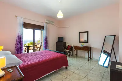 a bedroom with a bed and a desk and a window at Kalathas Sunset Villa in Kalathas