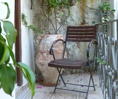 a wooden chair sitting on a porch with a plant at Splanzia Boutique Hotel in Chania Town