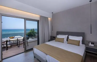 a bedroom with a bed with a view of the ocean at Creta Palm Resort Hotel & Apartments in Stalos