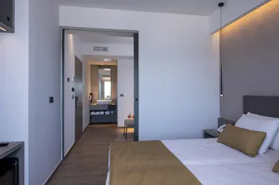 a bedroom with a large bed and a hallway at Creta Palm Resort Hotel & Apartments in Stalos
