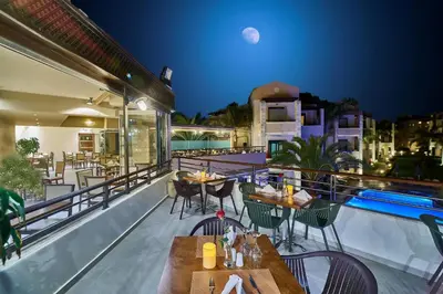 a balcony with tables and chairs and a pool at Creta Palm Resort Hotel & Apartments in Stalos
