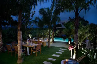 an outdoor dining area with tables and palm trees at night at Villa Emanuele in Gerani Chanion