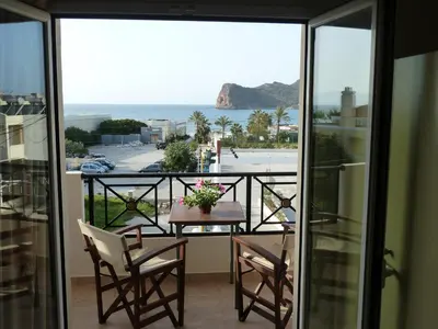 a balcony with a table and chairs and a view of the ocean at Mithos Apartments in Agia Marina Nea Kydonias