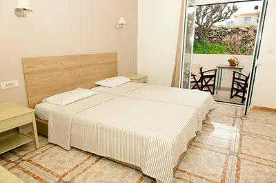 a bedroom with two beds and a balcony at Mithos Apartments in Agia Marina Nea Kydonias