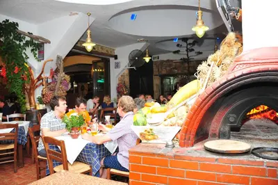 a group of people sitting at a table in front of a brick oven at Mithos Apartments in Agia Marina Nea Kydonias